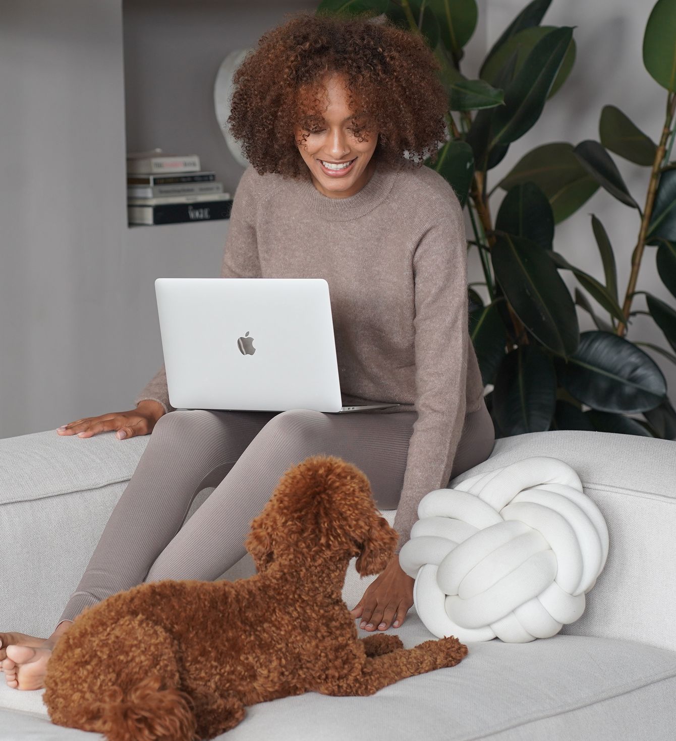 Frau mit Laptop und Hund auf dem Sofa